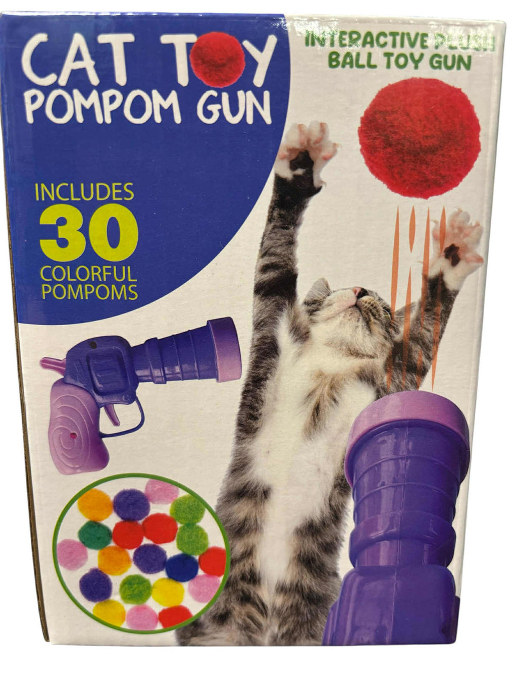 Boxed cat toy pom pom gun set with a purple ball gun, a red pom pom, and a circular inset showing 30 colorful pom poms. The packaging features a cat reaching for a red pom pom and bold text reading 'CAT TOY POMPOM GUN' and 'INCLUDES 30 COLORFUL POMPOMS'.