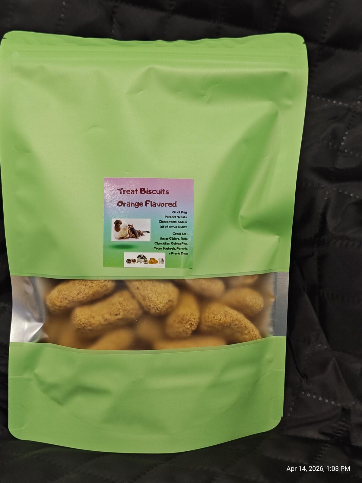Green package of orange-flavored treat biscuits on a black background