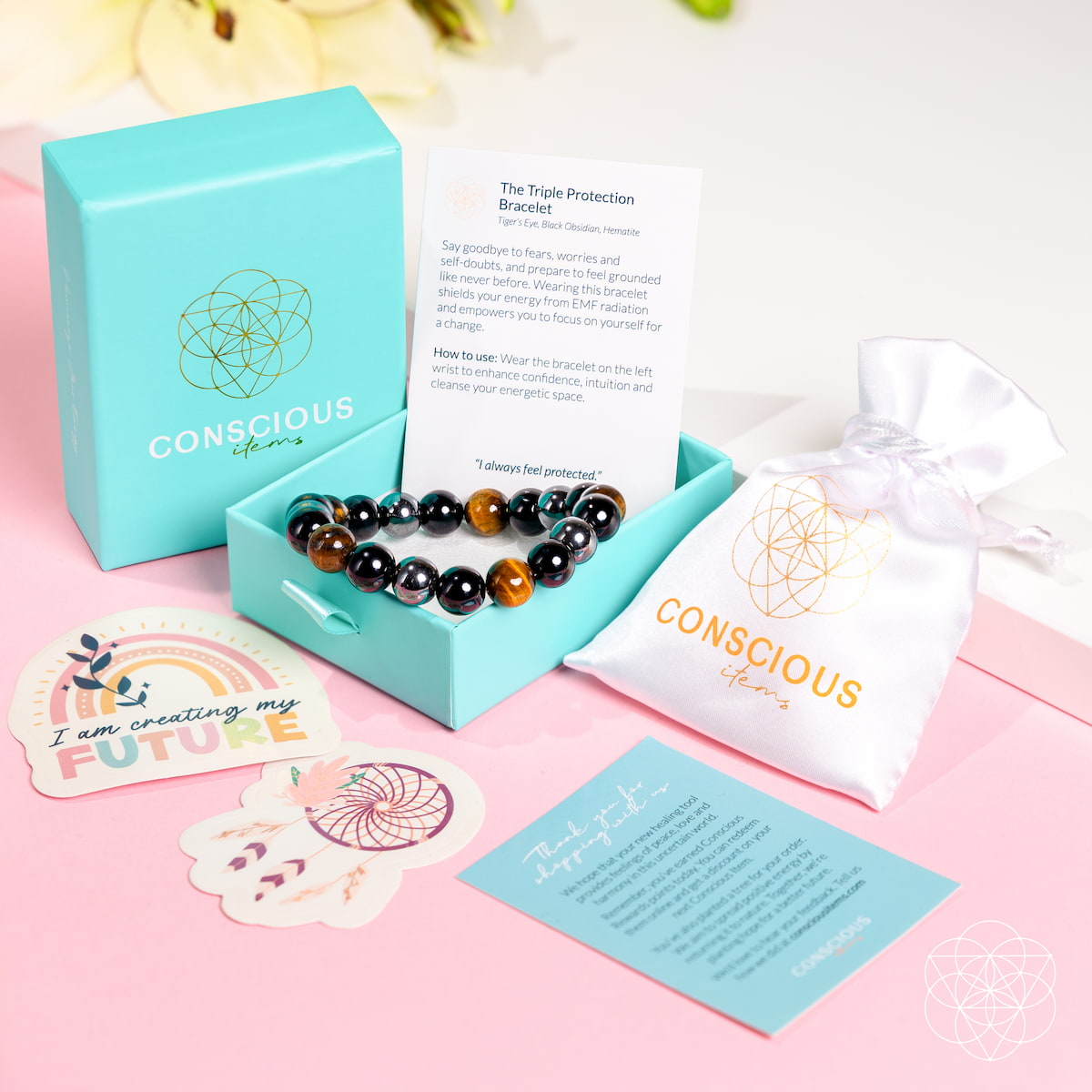 Triple Protection Bracelet in a turquoise Conscious Items box beside a white pouch and printed cards.