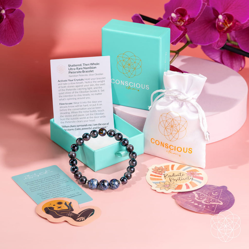 Pietersite and obsidian bracelet beside a turquoise Conscious Items box, white pouch, cards, and decorative stickers.
