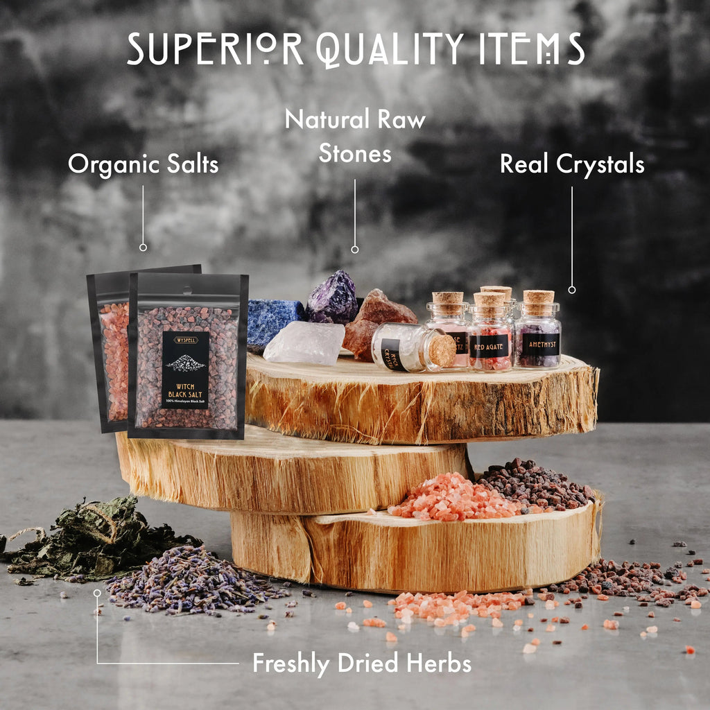 Dried herbs, pink and black salts, raw stones, and corked crystal jars displayed on stacked wood slices.
