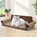 A fluffy white cat with blue eyes lies on a pet sofa made of dark brown wood and beige sisal rope, set in a bright room with light wood floors and potted plants.