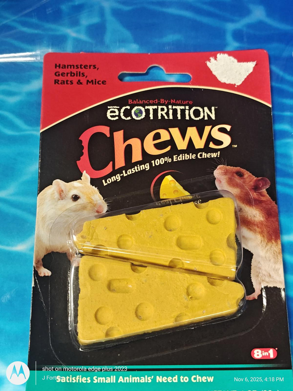 A package of ecotrition Chews hamster and gerbil edible chew toys, featuring two yellow cheese-shaped chews in a clear blister pack on a black and red backing card with pictures of a hamster and gerbil, set against a blue water-textured background.