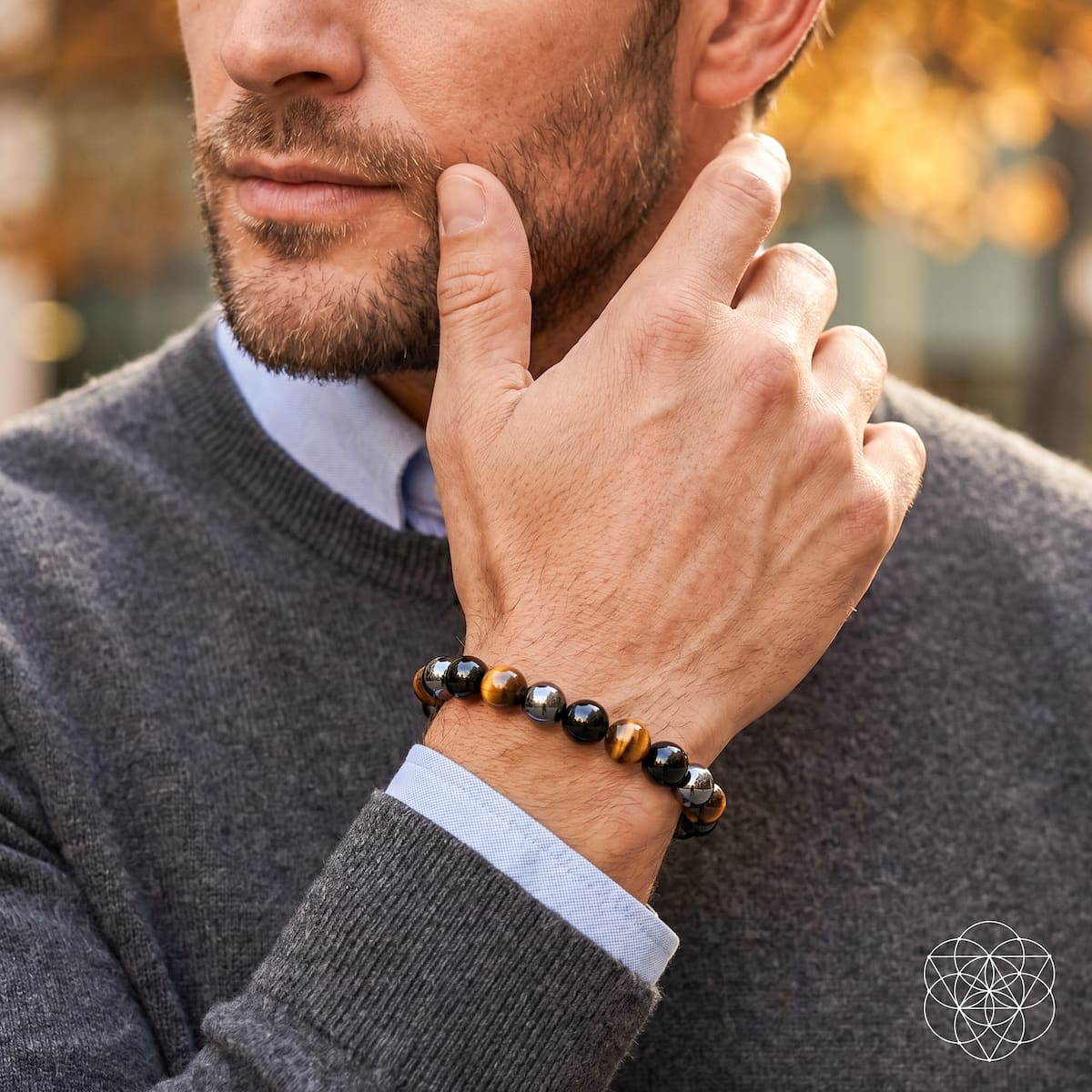 Man wearing the tiger’s eye, black obsidian, and hematite bracelet with a gray sweater and blue shirt.