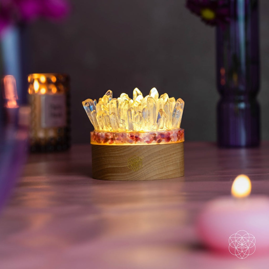 Quartz and tourmaline lamp casting a golden glow in a dim room beside purple vases and candles.
