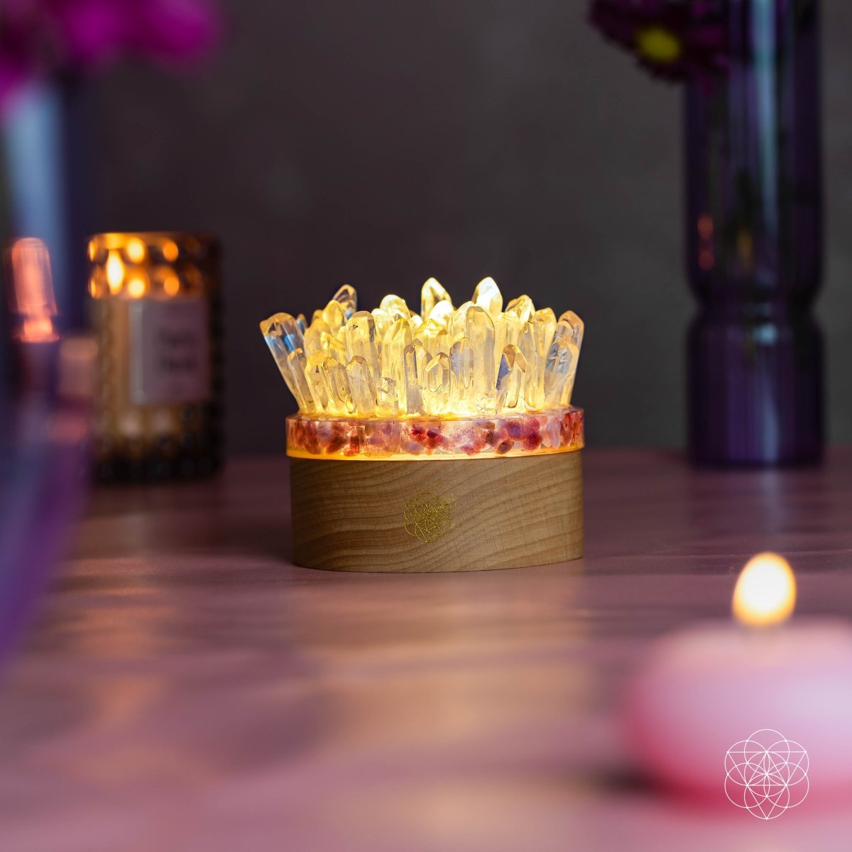 Quartz and tourmaline lamp casting a golden glow in a dim room beside purple vases and candles.
