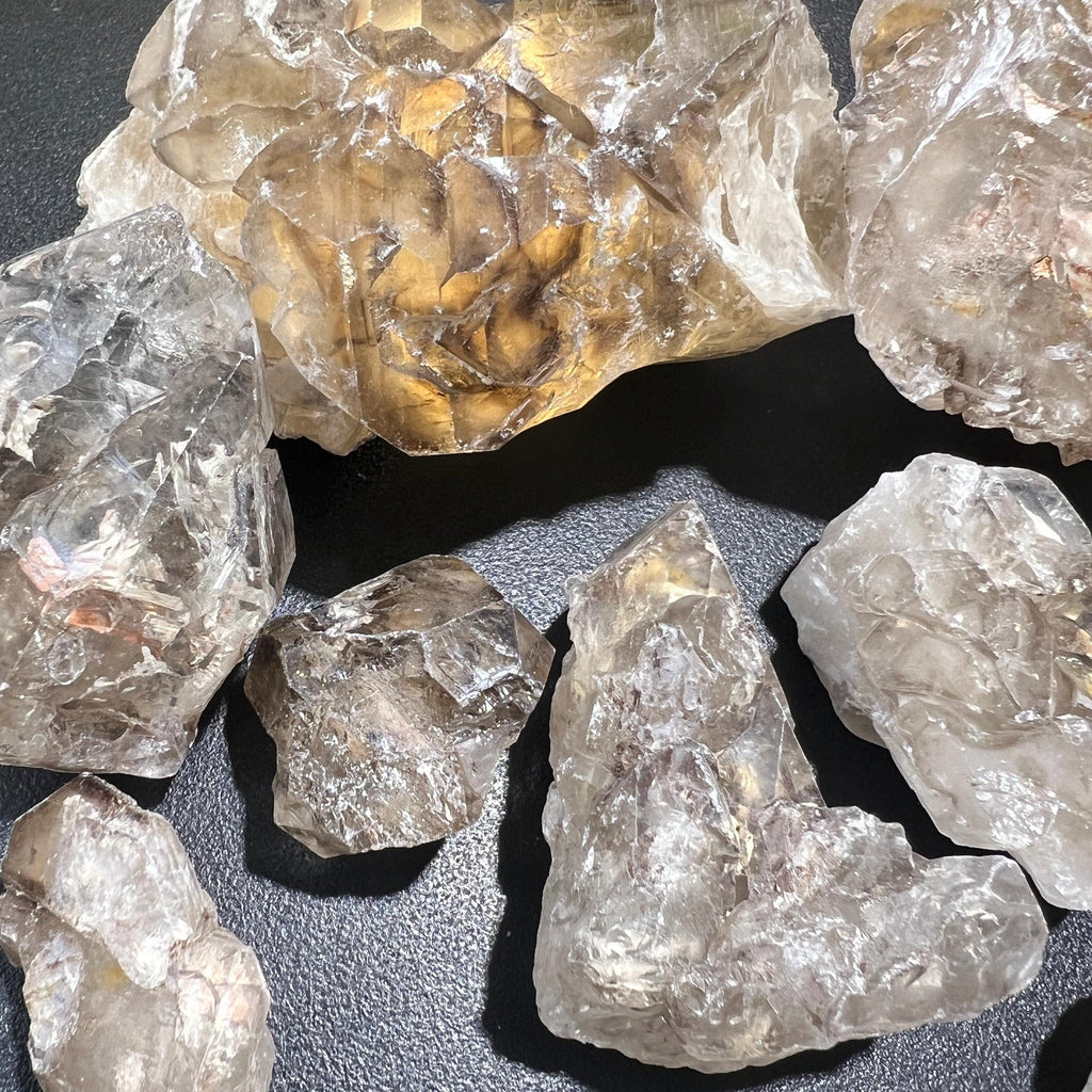 Rough elestial alligator quartz clusters with layered surfaces and a pointed L-shaped specimen in the foreground