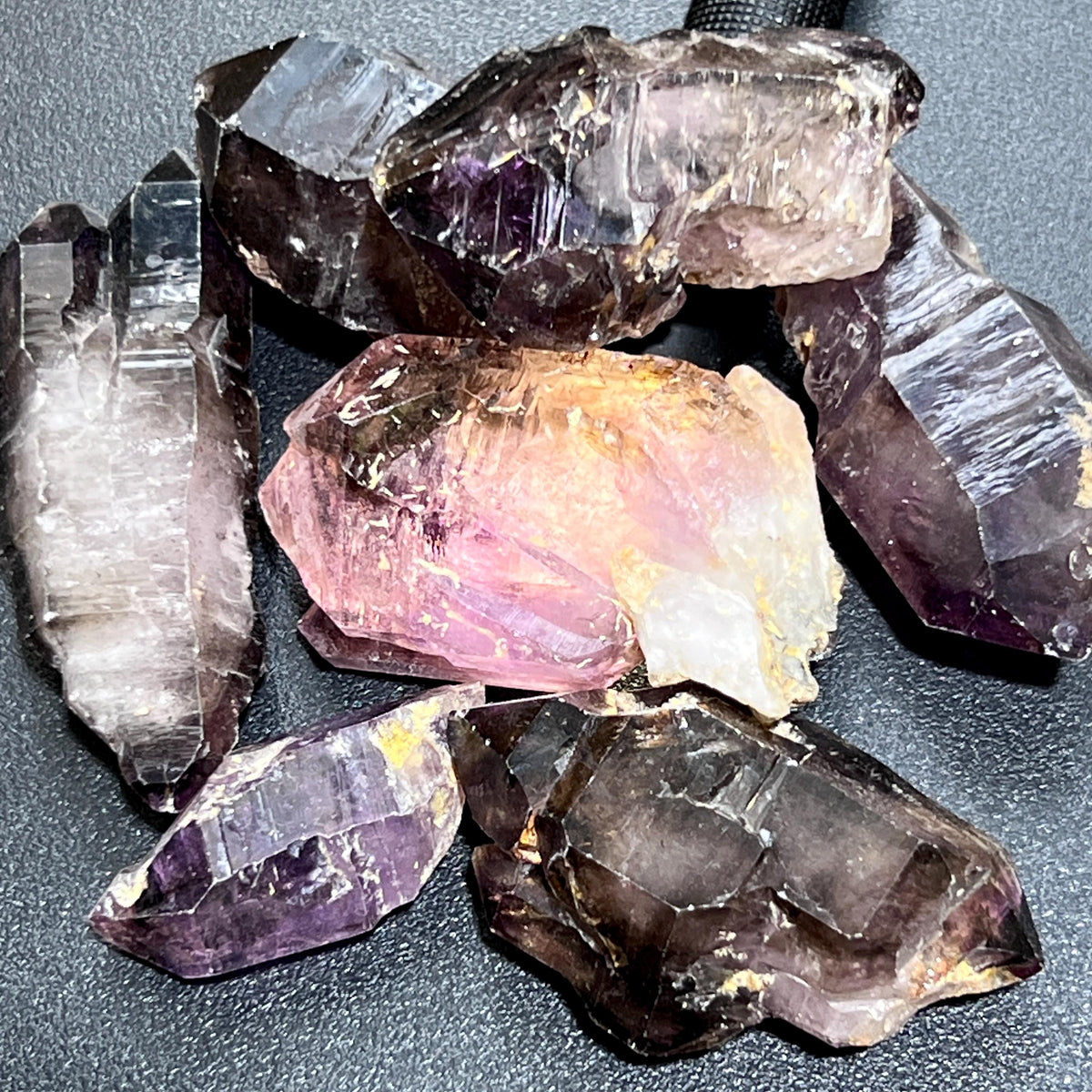 Assorted Shangaan amethyst crystals showing angular faces, purple interiors, smoky tips, and rough pale bases.
