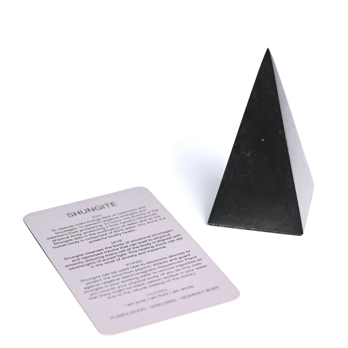 Tall black shungite pyramid displayed beside a printed Shungite information card on white.
