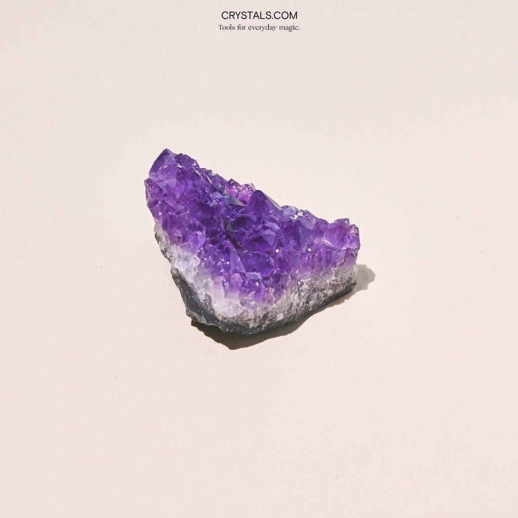 Triangular amethyst cluster with tall purple points and a pale band above a dark base.
