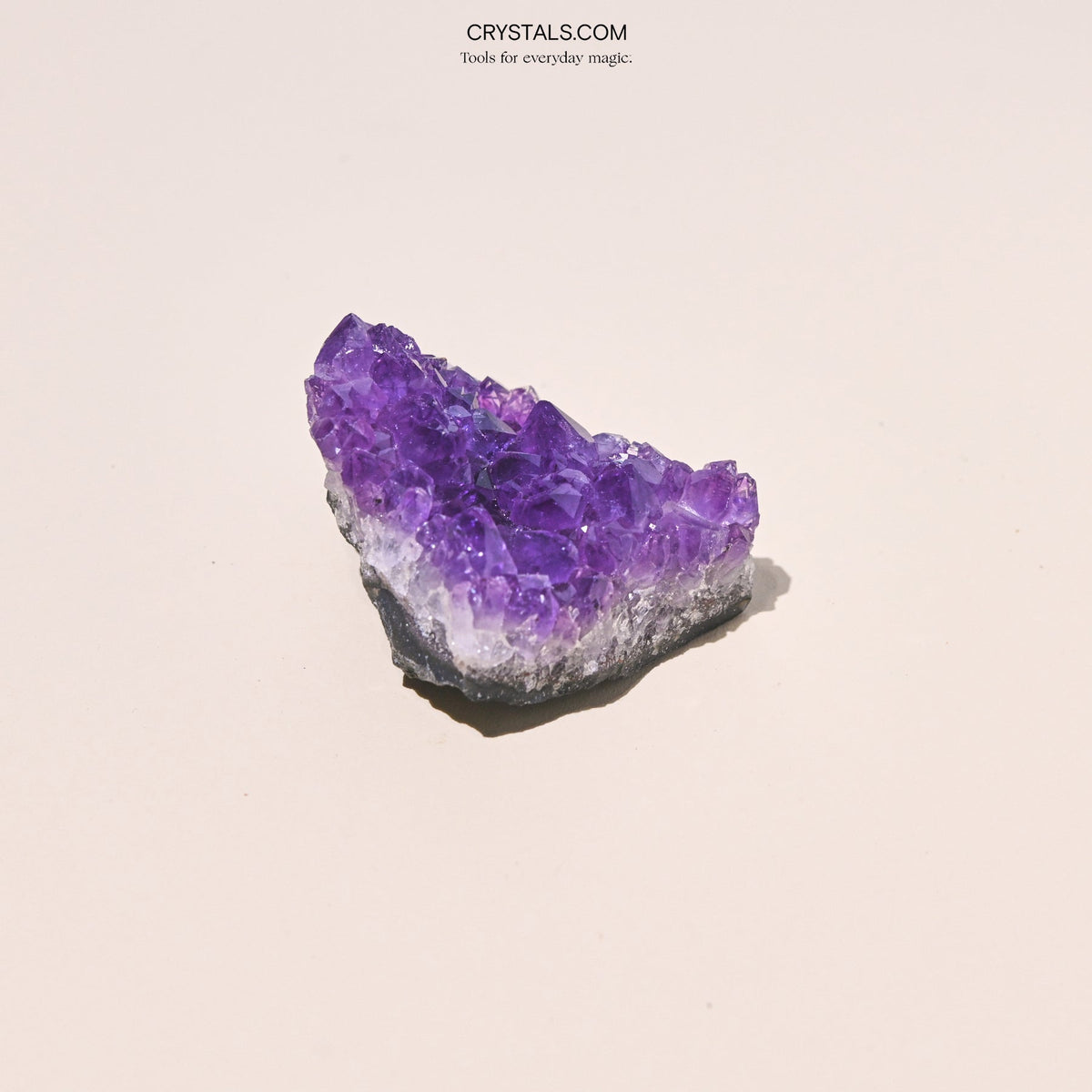 Triangular amethyst cluster with tall purple points and a pale band above a dark base.
