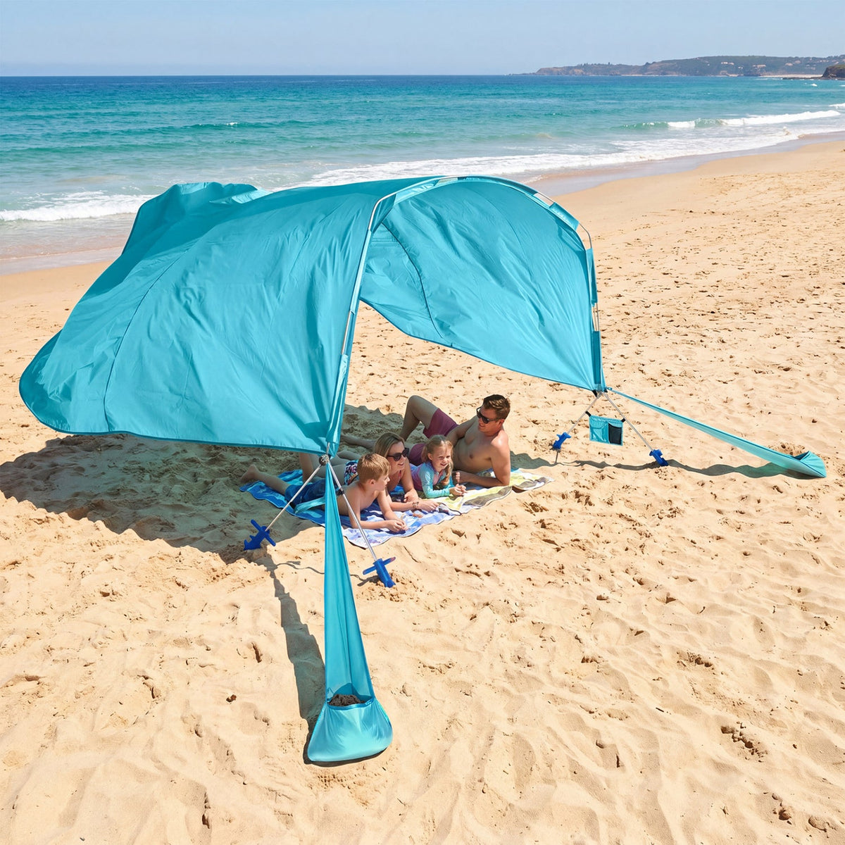 Family under a blue beach tent on a sandy beach with ocean view
