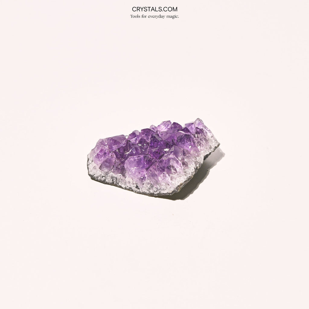 Small amethyst cluster with translucent lavender points and a pale stone border.
