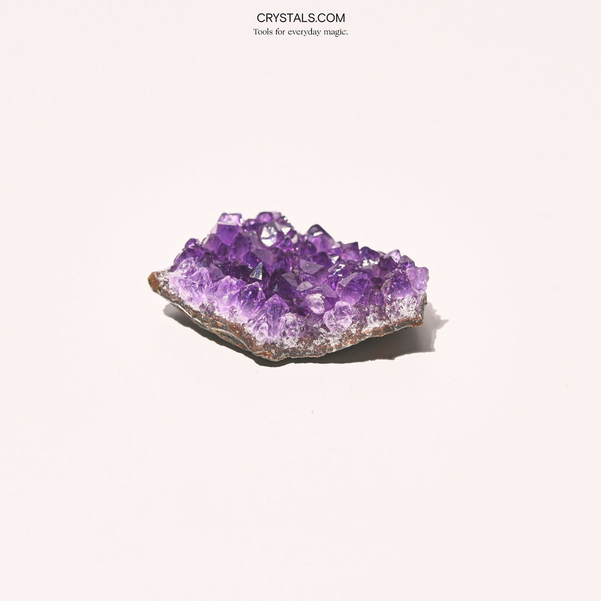 Low angled view of an amethyst cluster with lavender edges and darker purple crystal points.
