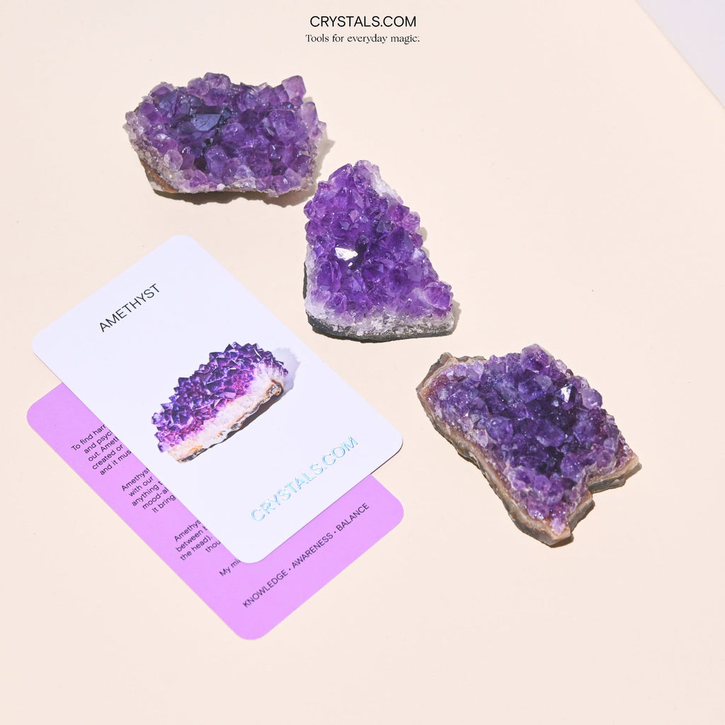Three amethyst clusters with prominent violet points displayed beside overlapping collector cards.
