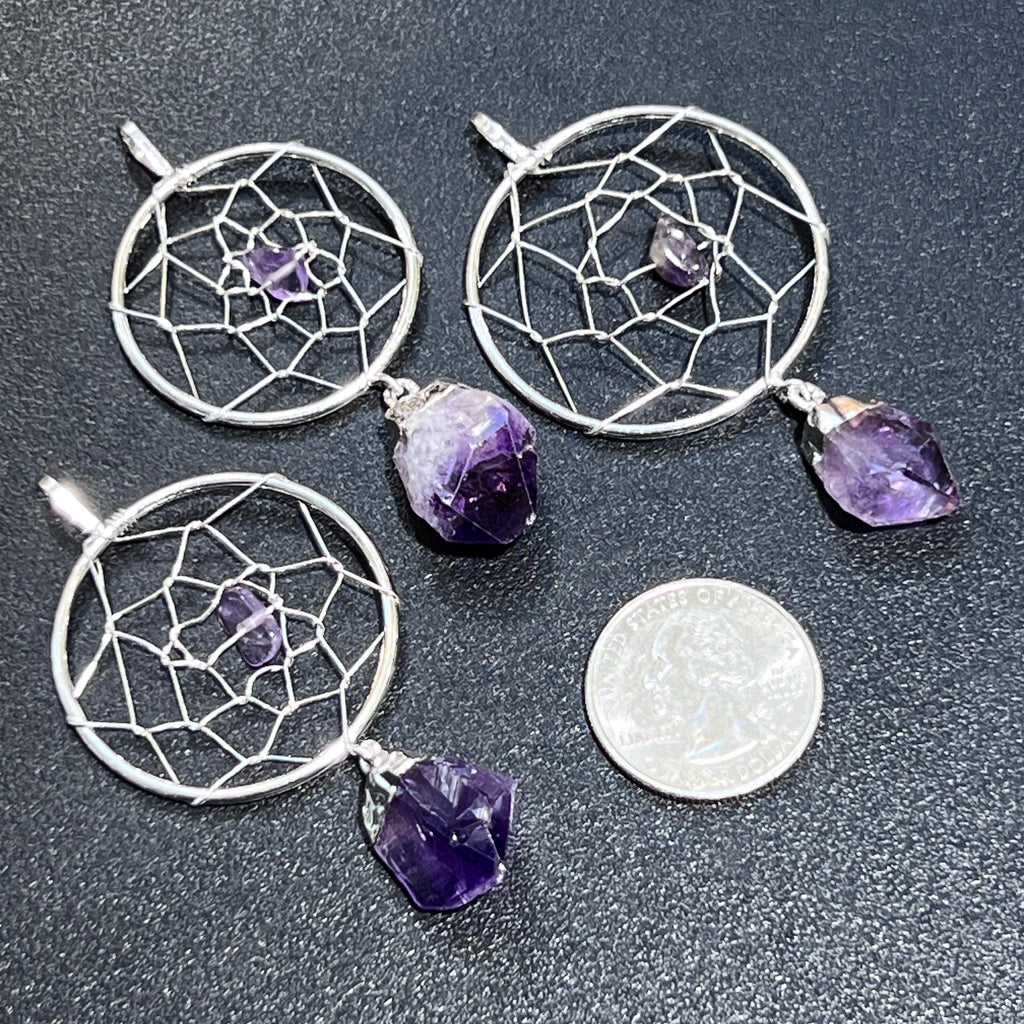 Three amethyst dreamcatcher pendants with circular silver-plated web designs beside a quarter for scale