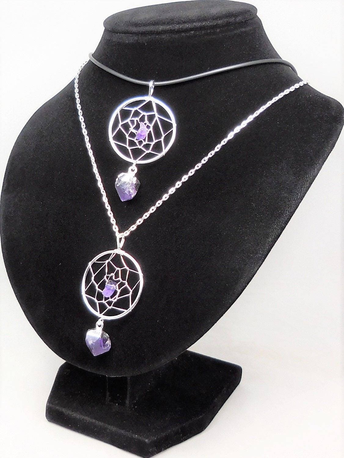 Two amethyst dreamcatcher pendants styled on a black necklace bust, one on a dark cord and one on a silver-colored chain