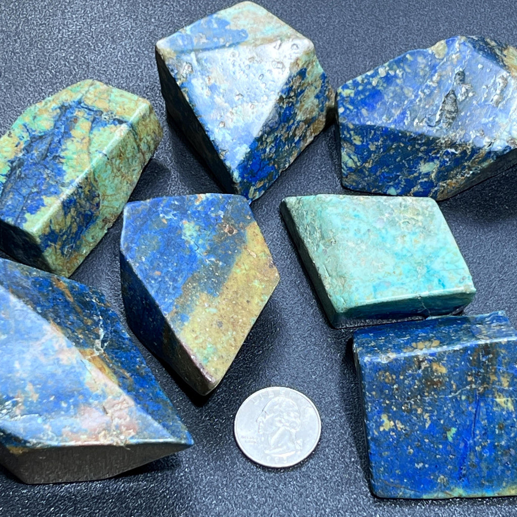 Polished azurite and chrysocolla freeforms with blue, green, and earthy patterns beside a quarter.