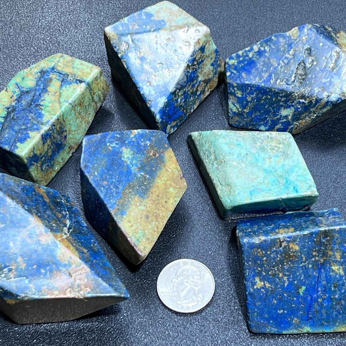 Polished azurite and chrysocolla freeforms with blue, green, and earthy patterns beside a quarter.