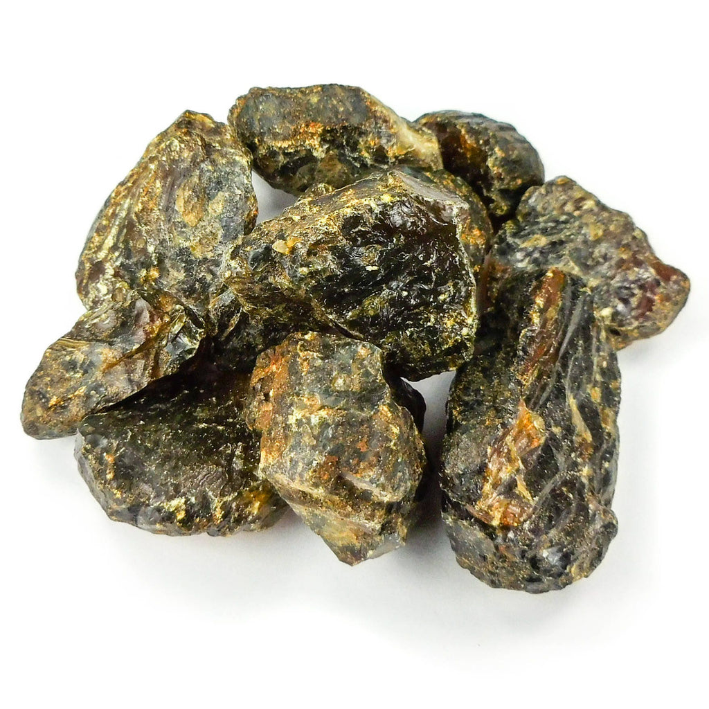 Pile of rough black amber resin pieces with glossy dark areas and golden brown crust on a white background