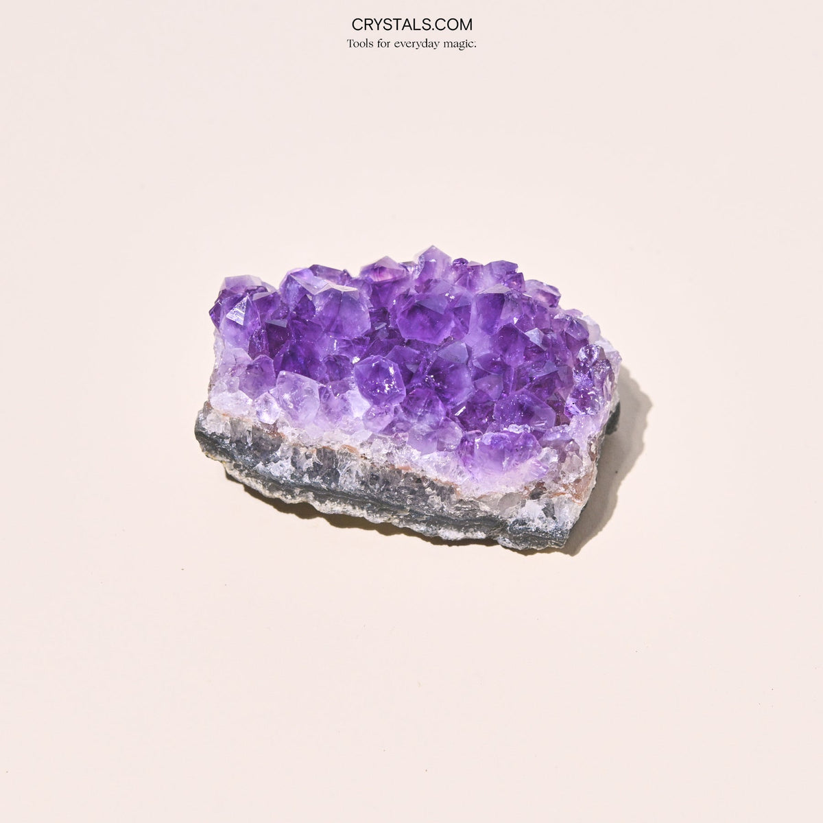 Close-up of a broad amethyst cluster with chunky lavender points and a layered pale and dark base.
