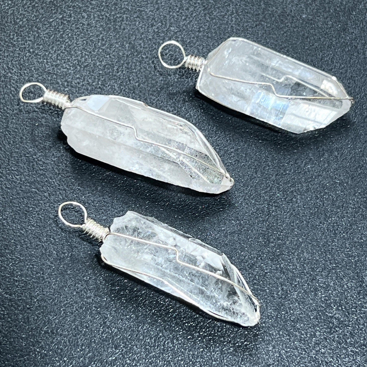 Three crystal pendants on a dark surface