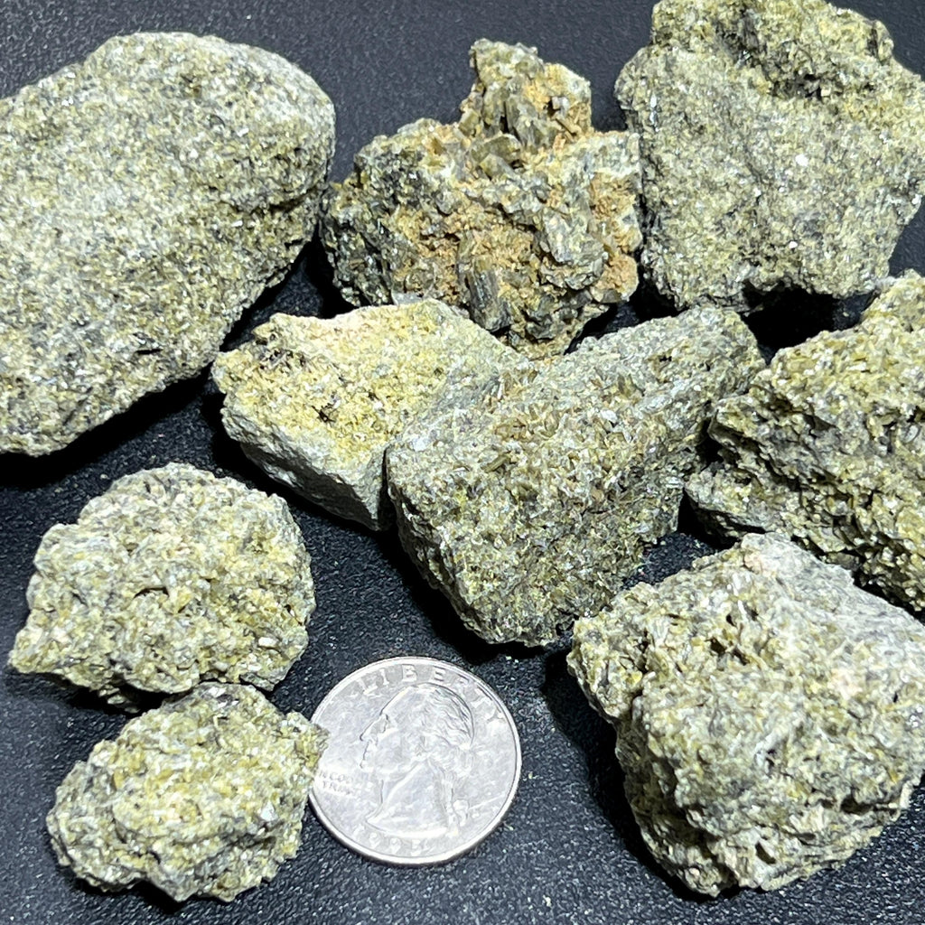 Green and gray-green raw epidote stones beside a quarter for size comparison.