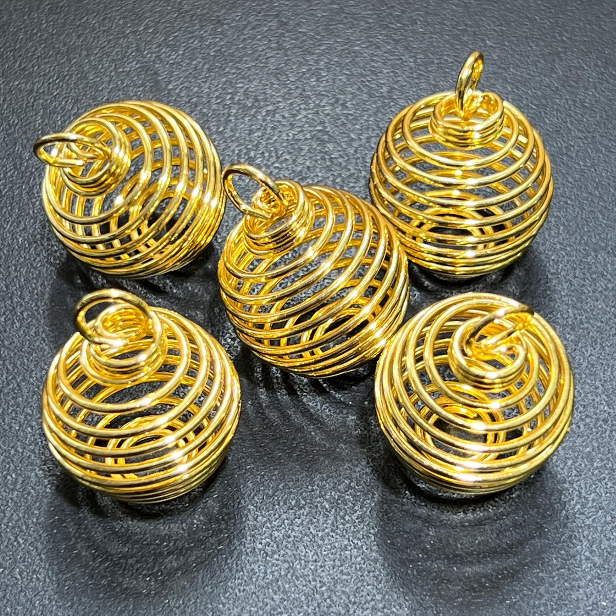 Five empty gold-finish sphere-shaped spiral cage pendants with attachment loops