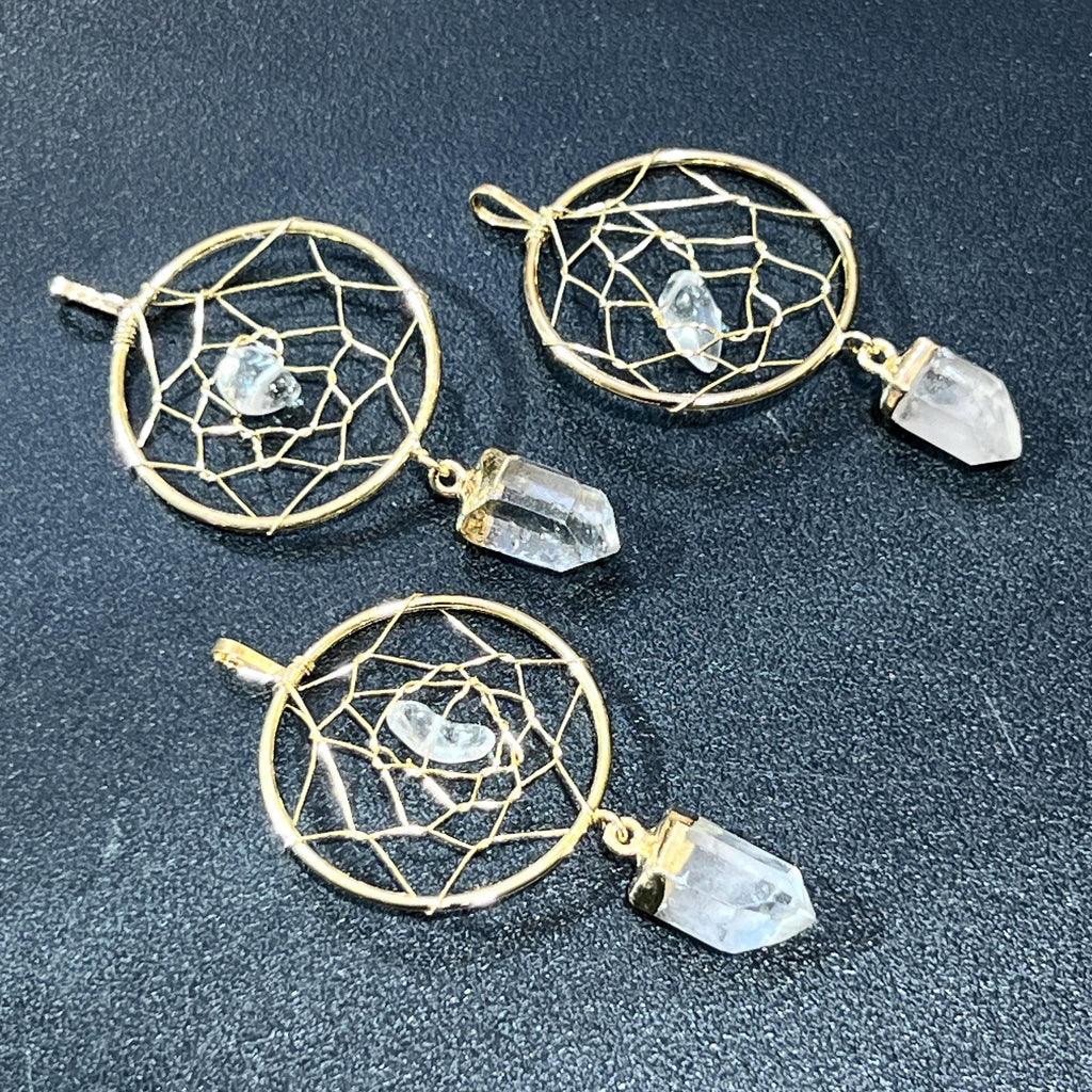 Three gold-plated dreamcatcher pendants with web-pattern hoops, small center crystals, and dangling clear quartz points.
