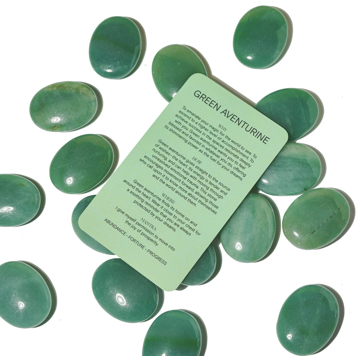 Green Aventurine information card resting over a group of polished green palm stones.
