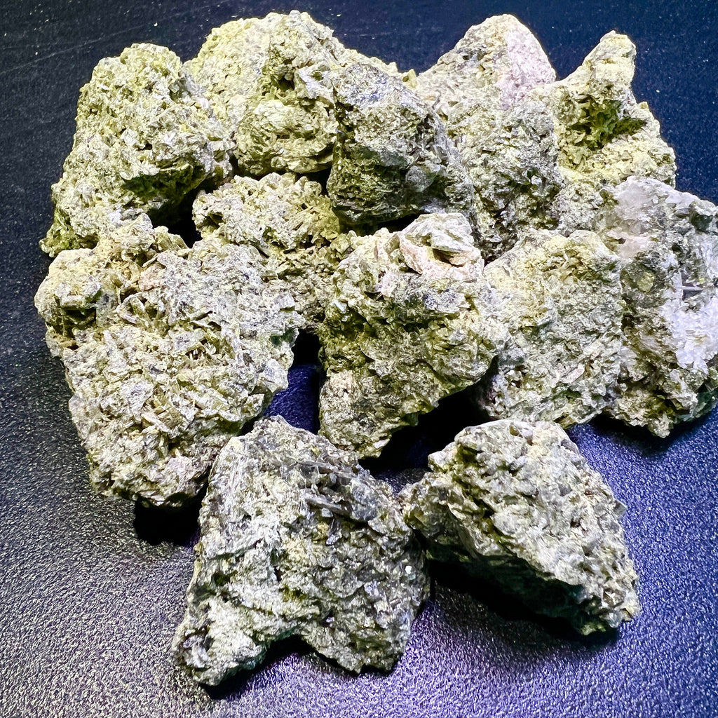 Assortment of rough green epidote crystal stones with rugged surfaces arranged on a dark textured background.