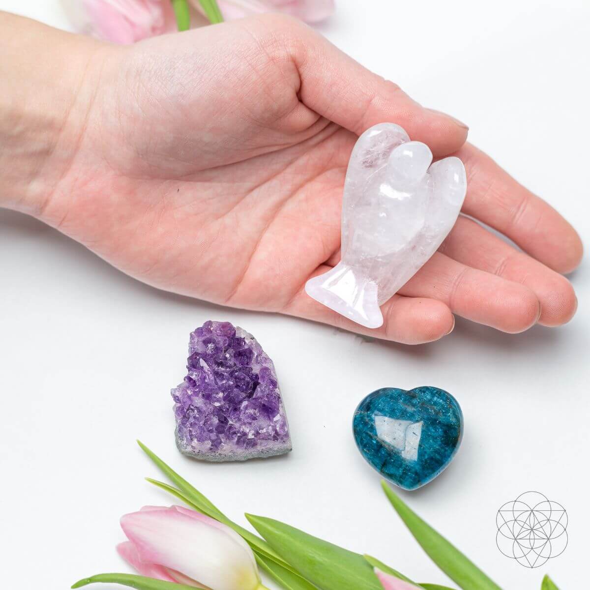 Hand holding a Clear Quartz angel above an Amethyst cluster and blue Apatite heart for size comparison.