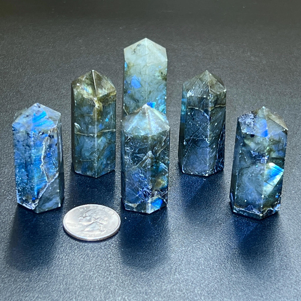 Small labradorite point towers showing blue and green flashes beside a quarter for scale