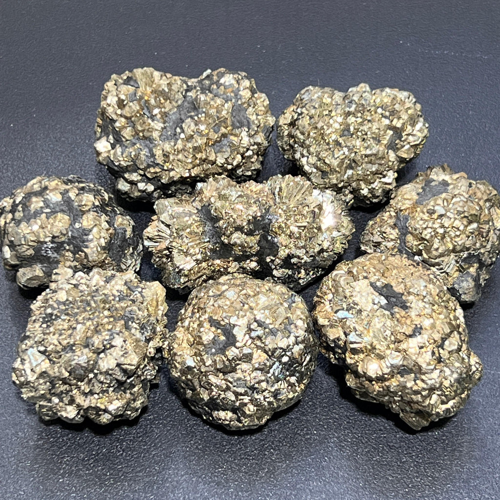 Eight irregular marcasite pyrite crystal nodules showing brass-gold clusters and dark patches on a black background