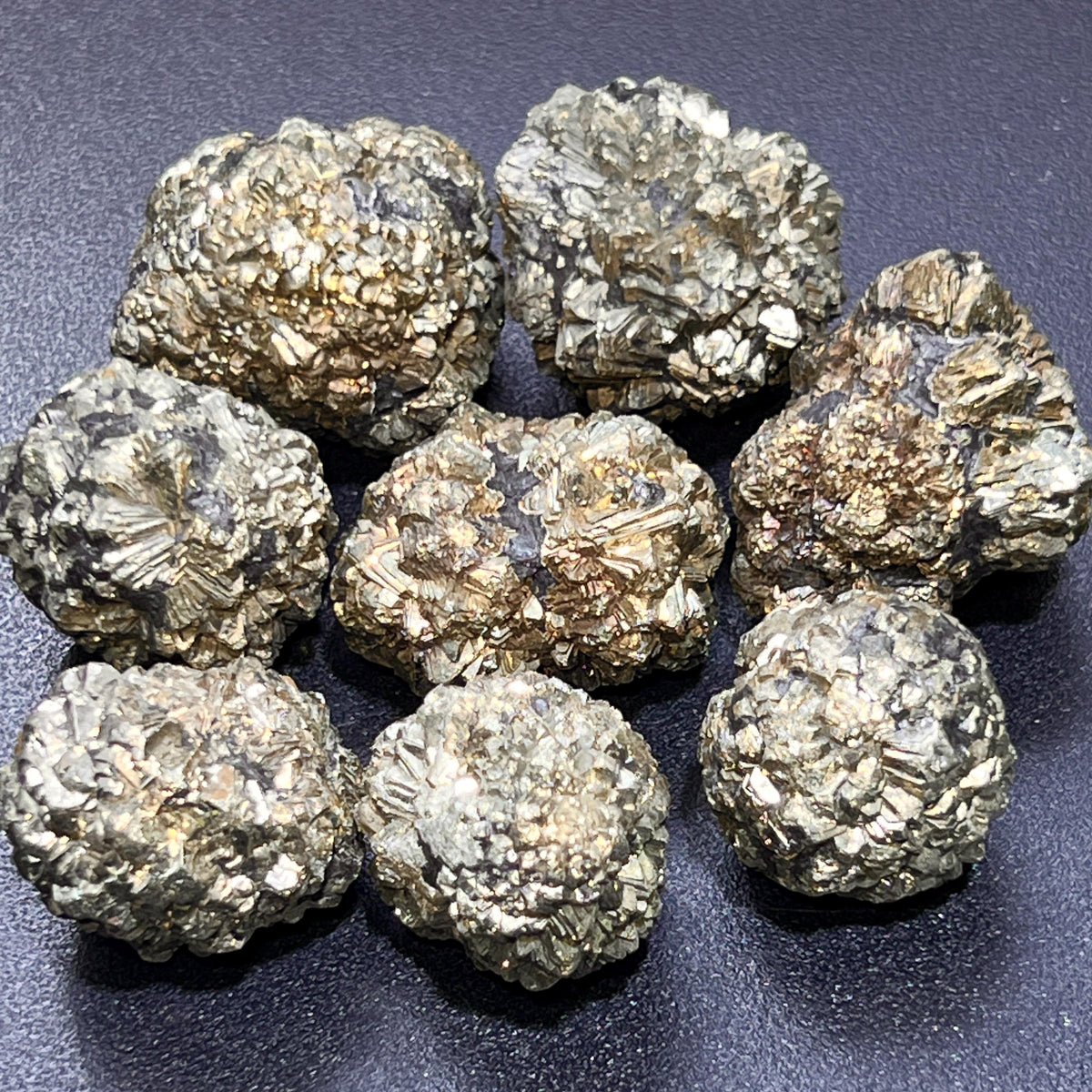 Group of eight rounded marcasite pyrite nodules with reflective angular crystals and fan-shaped surface textures