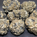 Close-up of metallic brass-gold crystal nodules with angular and radiating formations against dark gray areas