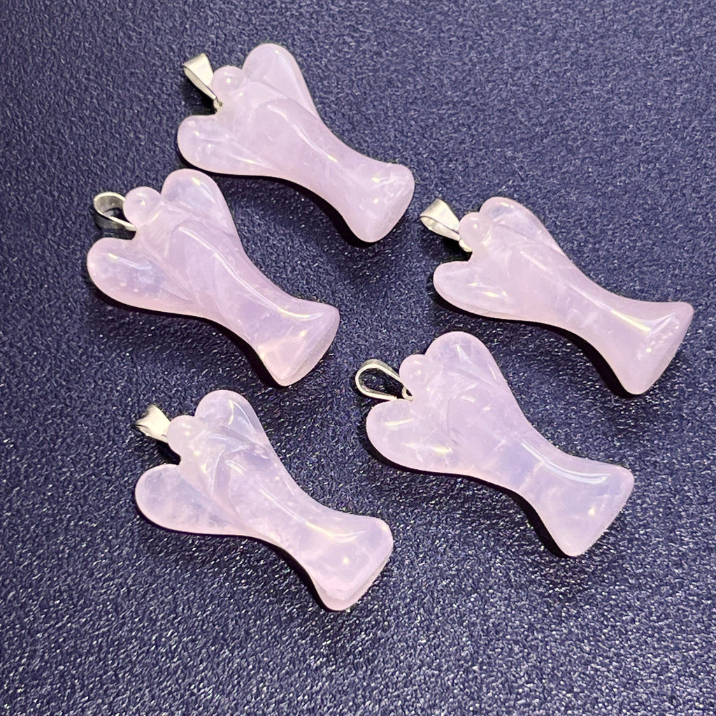 Five carved pink rose quartz angel pendants showing rounded wings and silver-tone hanging bails on a dark surface.
