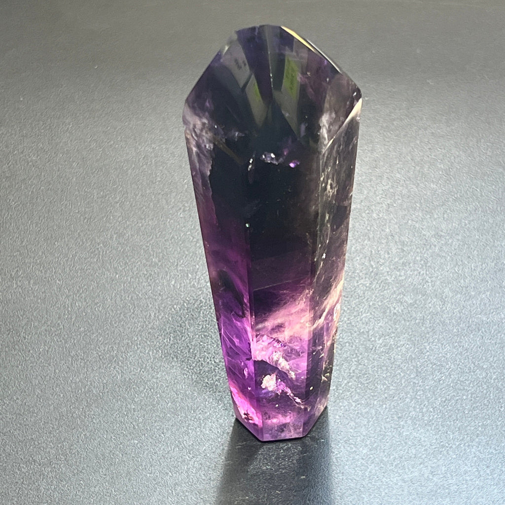 Single tall polished amethyst tower standing upright with a dark purple top and translucent violet base