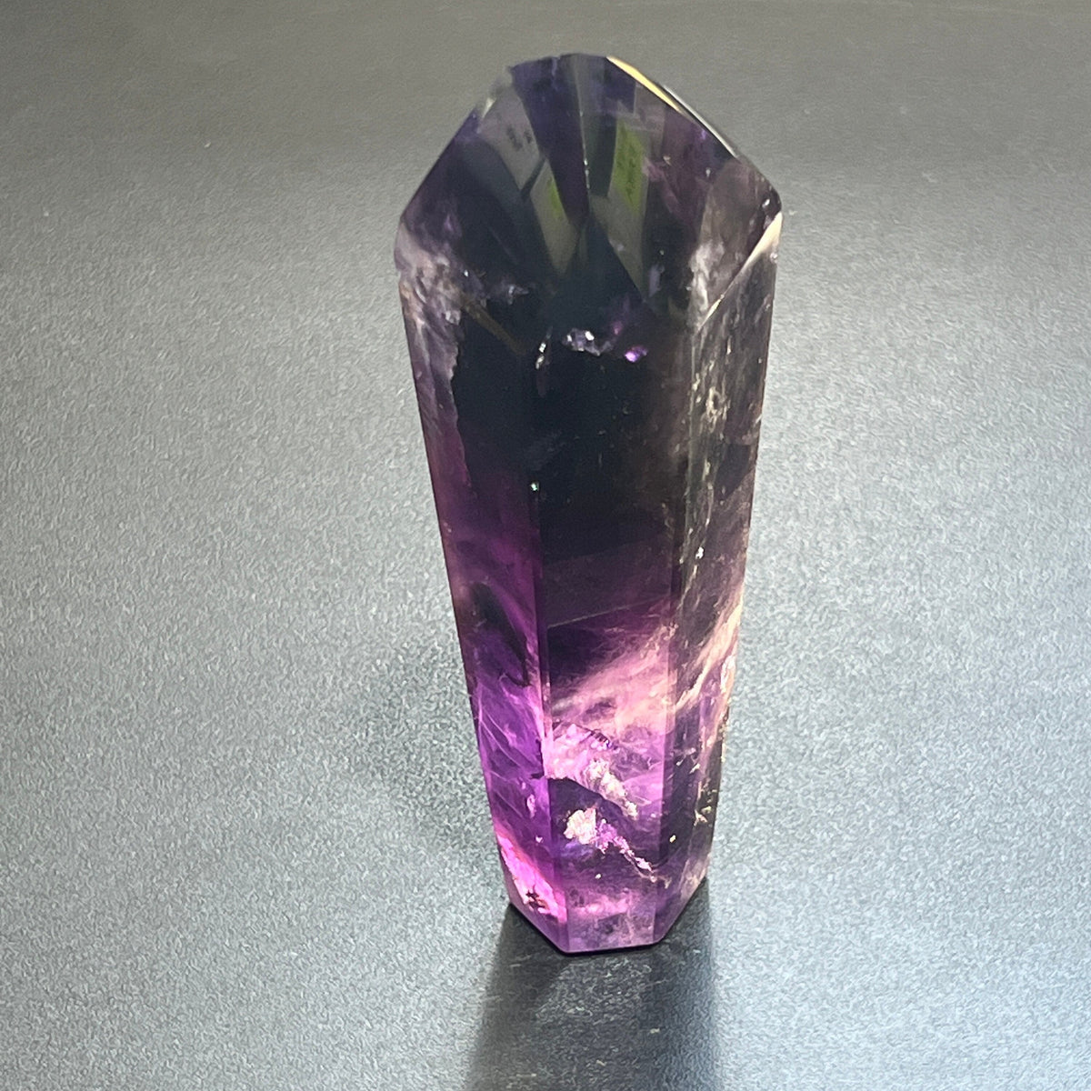 Single tall polished amethyst tower standing upright with a dark purple top and translucent violet base