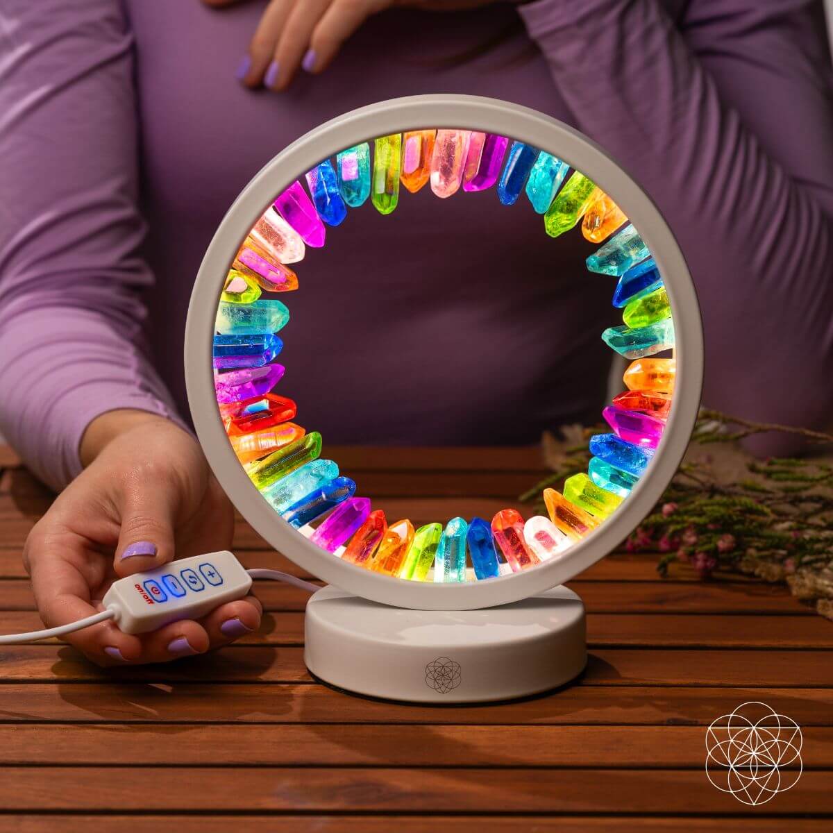 Person holding the wired inline controller beside an illuminated white rainbow aura quartz halo lamp.
