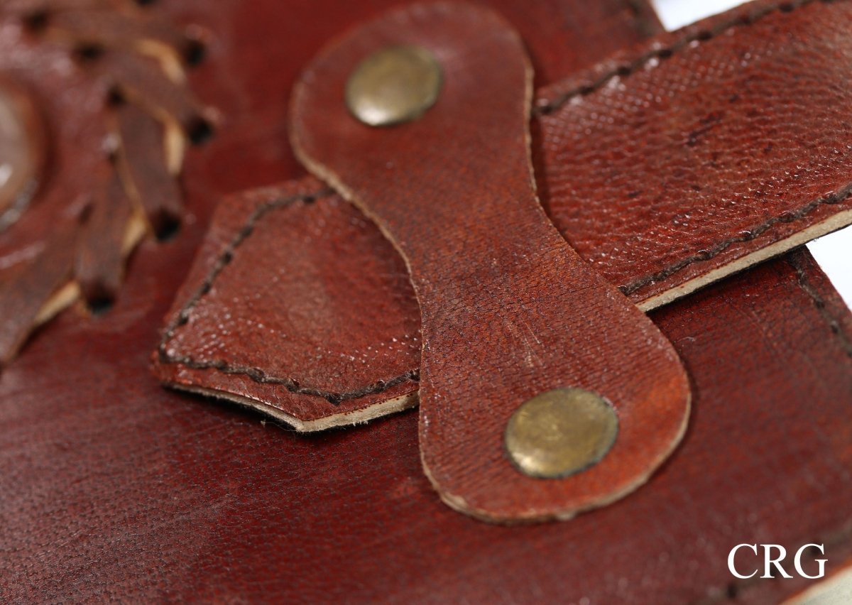 Close-up of brown leather journal strap with stitching and two metal rivets