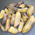 Assorted rough citrine crystal points in pale golden and smoky tones arranged on a dark textured surface