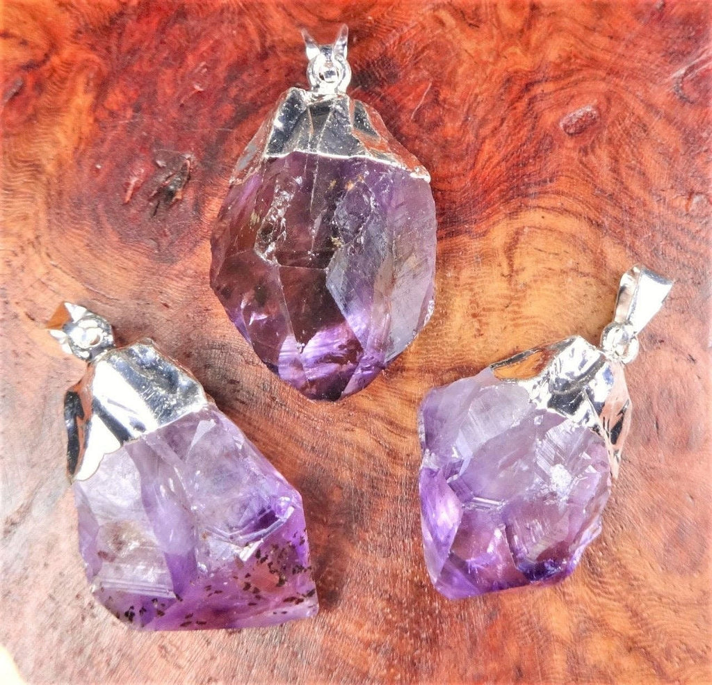 Three purple crystal pendants on a wooden surface