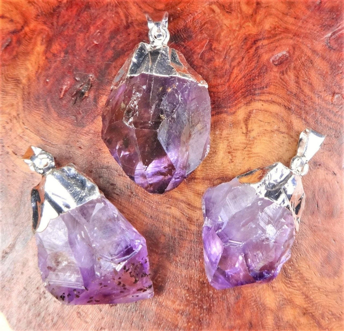 Three purple crystal pendants on a wooden surface