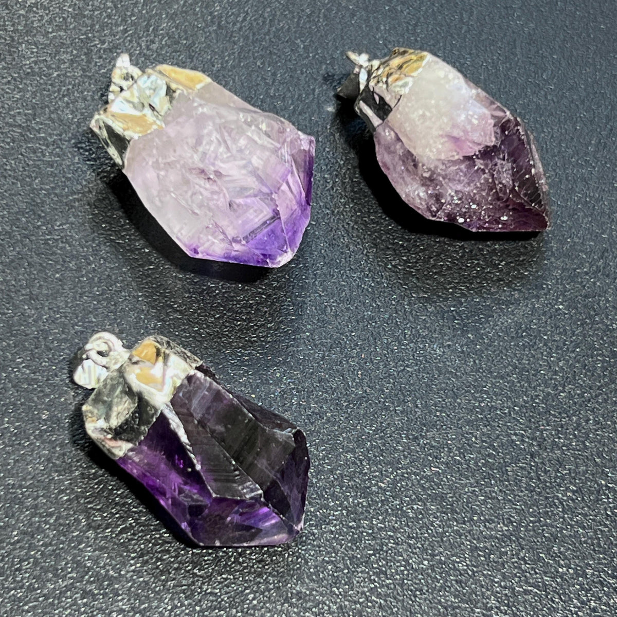 Three amethyst crystals on a dark surface