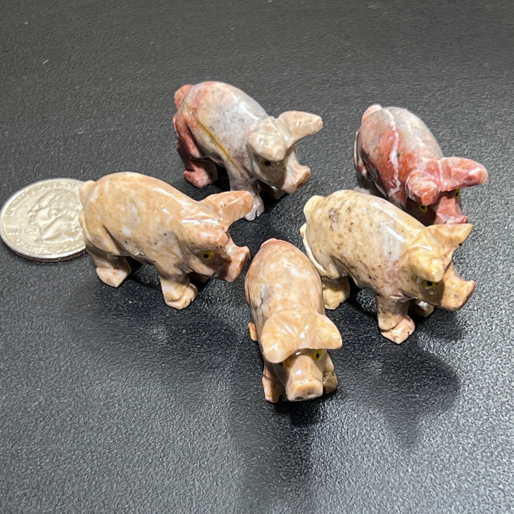 Five miniature soapstone pig figurines in cream, tan and pink with carved snouts beside a coin