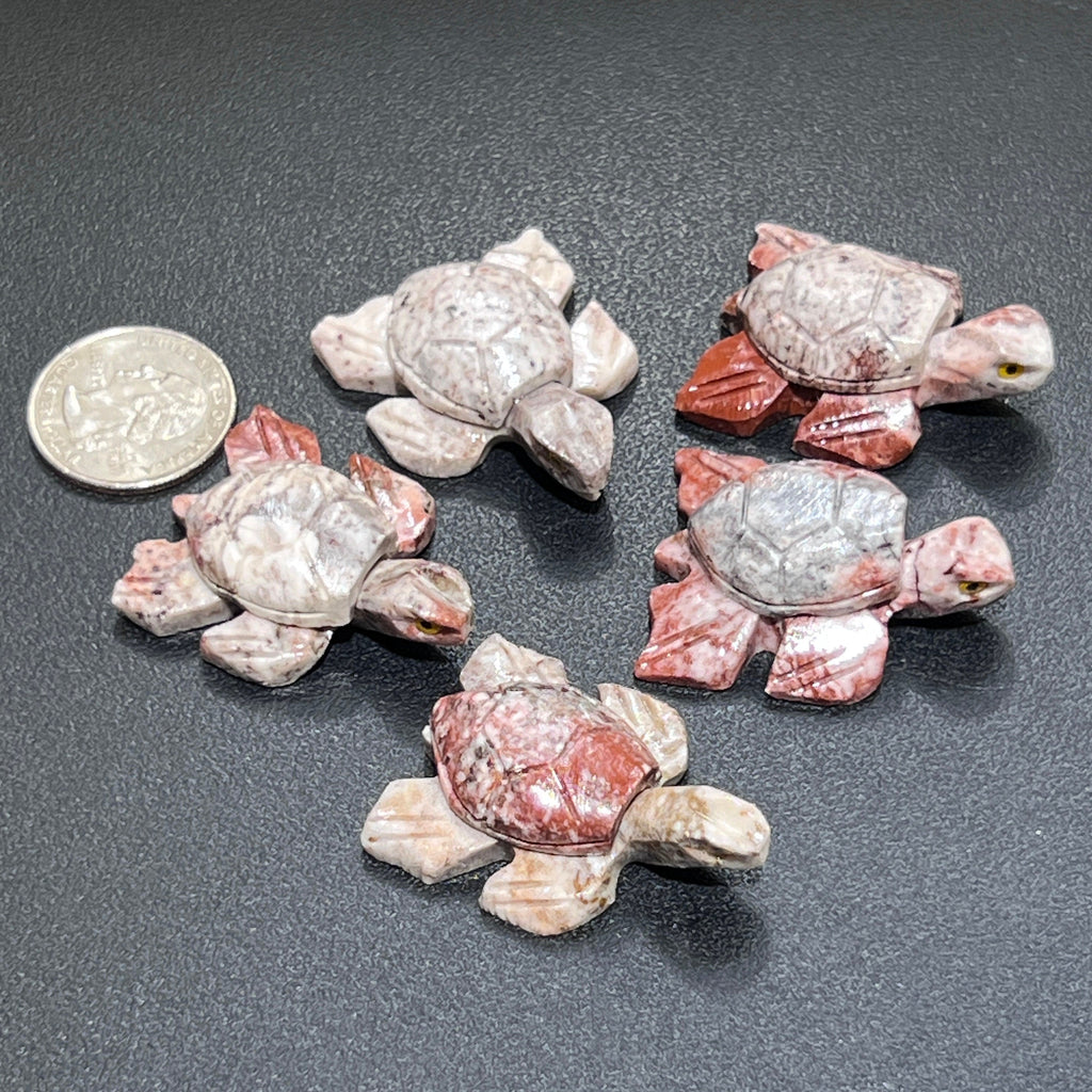  Five miniature soapstone sea turtles with carved shell patterns in pink and cream tones beside a coin