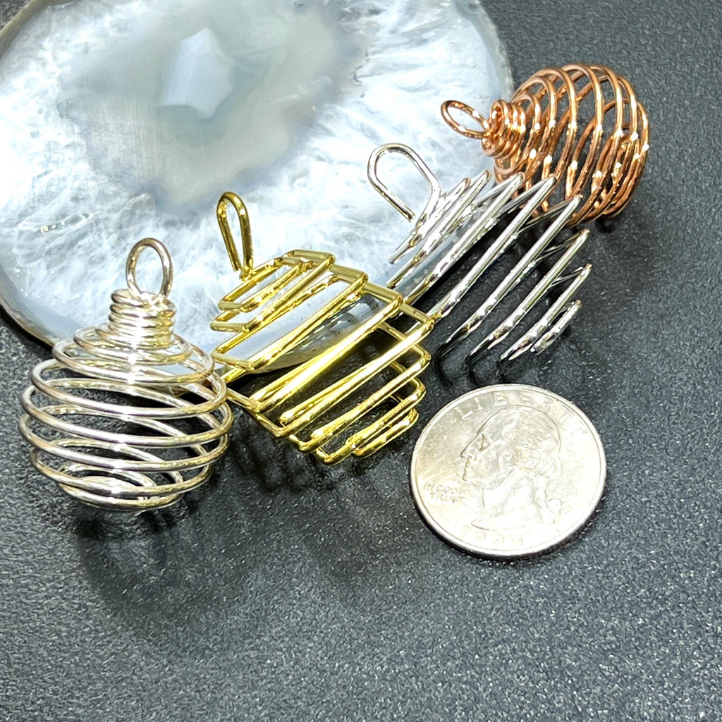 Assorted empty metal spiral cage pendants beside a quarter for scale on a dark surface
