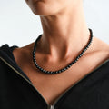 Model wearing a glossy black shungite bead necklace with a black zip-front top.
