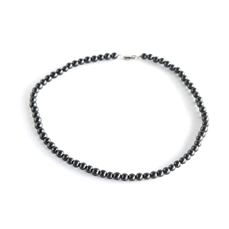 Single-strand black shungite bead necklace arranged in a circle with a metal clasp on a white background.
